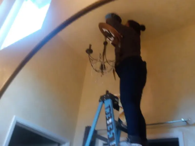 Electrician installing a chandelier in a Welsh residence
